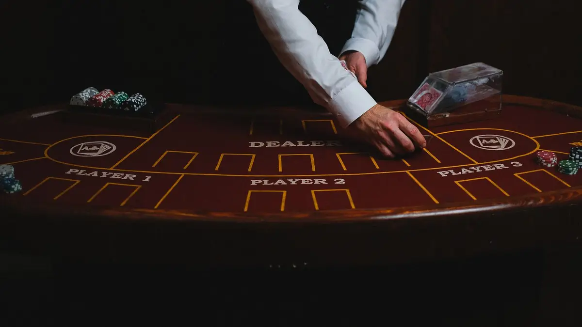 A dealer's hands working a table marked for three player positions